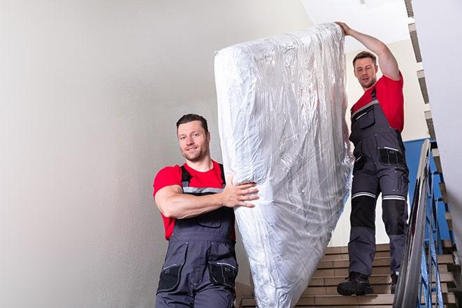 team of workers lifting a box spring out of a house in Macedonia